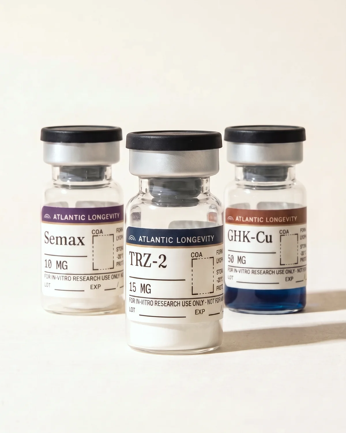 Semax 10 mg, TRZ-2 15 mg and GHK-Cu 50 mg vials in a row on bone paper, the GHK-Cu vial half-filled with copper-blue solution